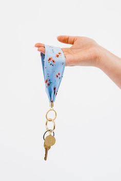 a person's hand holding a key chain with a blue bandana around it