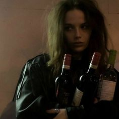 a woman holding three bottles of wine in her hands