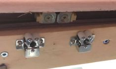 two metal latches are attached to the side of a wooden door with screws