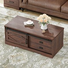 a wooden coffee table with two drawers on top and flowers in vases on the bottom