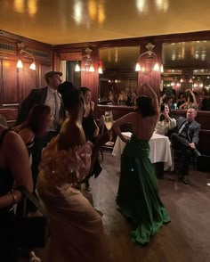 a group of people in formal wear dancing at a wedding reception with guests seated around the tables