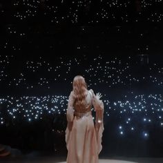 a woman standing in front of a stage with lights on it's sides and her back to the camera