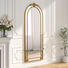 a large gold framed mirror sitting on top of a wooden floor next to a fireplace