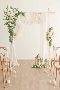 the wedding arch is decorated with white flowers and greenery