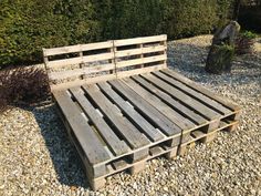 a bed made out of wooden pallets sitting on gravel next to a rock garden