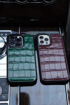 three cell phones sitting next to each other on top of a wooden table in front of a camera