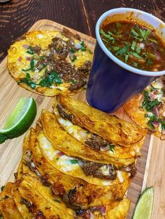 tortillas with meat, cheese and sauce on a cutting board next to a cup of soup