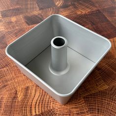 a white square container sitting on top of a wooden table next to a cup holder