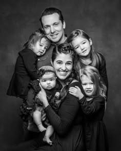 a black and white photo of a family posing for the camera with their two children