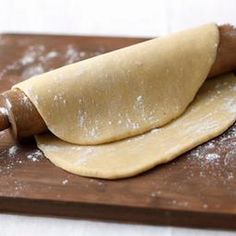 a rolling dough on top of a wooden cutting board