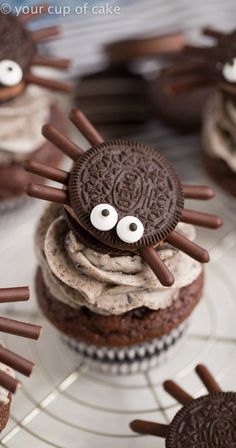 chocolate cupcakes decorated with oreo cookies and spider eyes are on a wire rack