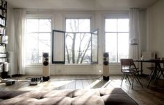 a living room with bookshelves, windows, and a couch in front of it