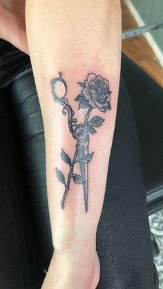 a person with a tattoo on their arm holding a rose and a knife in the other hand