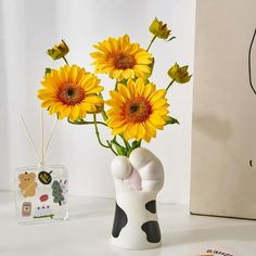 a vase with yellow flowers in it next to a card holder