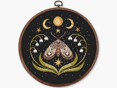 a cross stitched picture of a moth on a black background with stars and moon