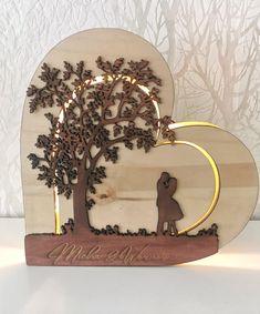 a couple kissing under a tree on a wooden plaque