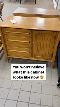 a wooden cabinet sitting on top of a tiled floor next to a blue trash can