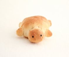 a small stuffed animal laying on top of a white surface with one eye open and the other half closed