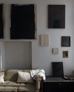 a living room filled with furniture and paintings on the wall above it's windows