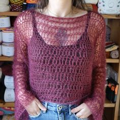 a woman standing in front of a shelf full of yarns and crochet