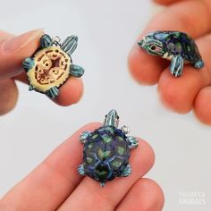 two tiny turtle figurines are being held by someone's hand with their fingers