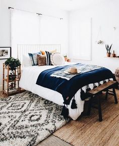 a bedroom with a bed, rugs and plants on the floor next to it