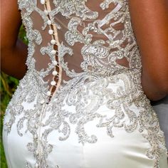 the back of a bride's wedding dress with beading and pearls on it