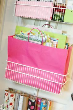 a shelf filled with lots of wrapping paper next to a wall mounted mailbox holder