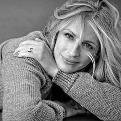 a black and white photo of a woman with her hand on her shoulder, leaning against the wall