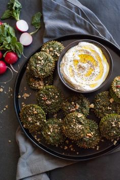 broccoli bites are arranged on a black plate with a dip in the middle