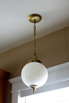 a light fixture hanging from the ceiling in a room with wood paneling and white walls