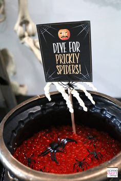 halloween decorations are displayed in a pot with red liquid and fake spider legs on top