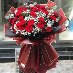 a bouquet of red roses wrapped in black paper