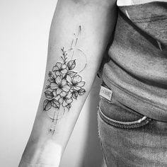 a black and white photo of a flower tattoo on the left arm, with an arrow in the middle