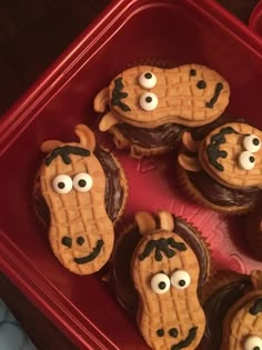 some cupcakes with googly eyes are in a plastic container on a table