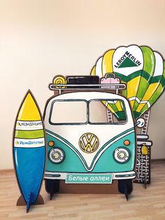 a vw bus with surfboards on the front and back stands against a wall