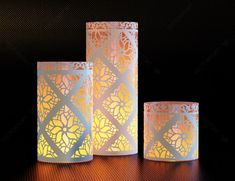 three lit candles sitting next to each other on top of a wooden table in front of a black background