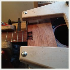 a close up of a guitar being worked on with woodworking equipment in the background