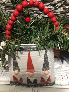 a tin can decorated with christmas decorations and red balls on the top, sitting on a table