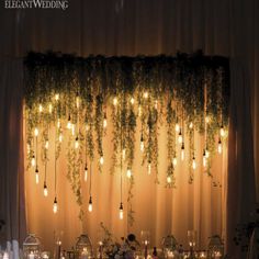 the wedding table is set up with candles and greenery hanging from the ceiling above it