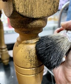 a close up of a person shaving a wooden pole with a brush on it