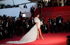 a woman in a white dress standing on a red carpet next to photographers and papas