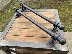 a metal and wood table with two handles on it's sides, sitting in the grass