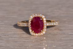 an oval shaped ruby and diamond ring on a wooden surface