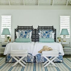 two beds in a bedroom with blue and white decor