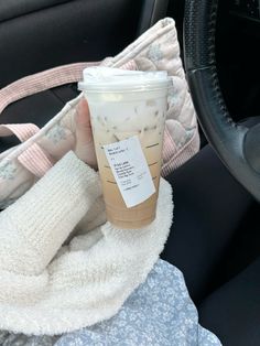 a cup of coffee sitting on top of a blanket next to a car steering wheel