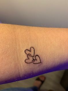 a person with a tattoo on their arm holding two hearts in the shape of a heart