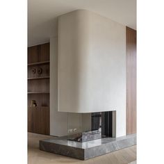 a modern fireplace in the middle of a living room with wood and marble accents on the mantle