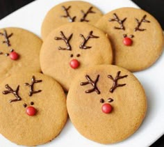 six cookies decorated with reindeer faces and noses on a white plate, ready to be eaten