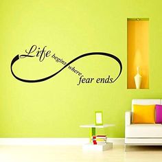 a living room with a couch and wall decal that says life begins when fear ends